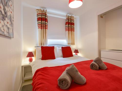 a bedroom with a red bed with two towels on it at SoundView in Plymouth