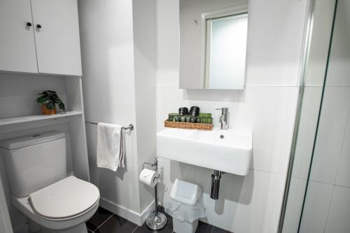 a white bathroom with a toilet and a sink at ‘Sunrise on Aura’ Apartment with stunning views. in Melbourne