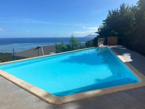 a large blue swimming pool with the ocean in the background at Punaauia Panoramic View in Punaauia