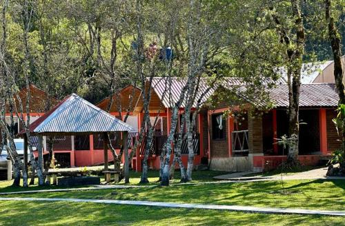 a red house with trees in front of it at Cabañas Junkolal Tziscao in Santiago