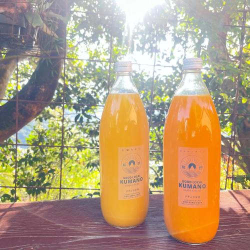 two bottles of orange juice sitting on a wooden table at ATASHIKADAYS Kumano-Kodo Beachfront B&B Hostel in Kumano