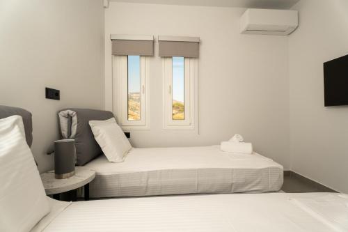 a white bedroom with two beds and a window at Koumbara Sea View in Ios Chora