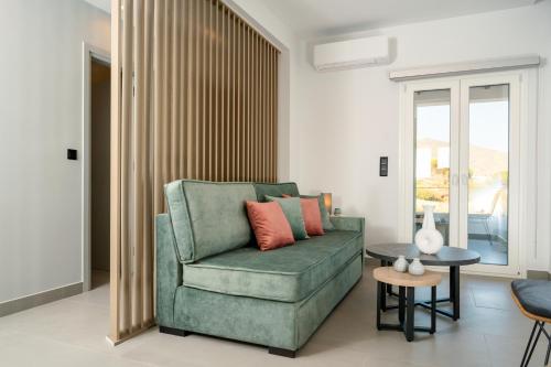 a living room with a green couch and a table at Koumbara Sea View in Ios Chora