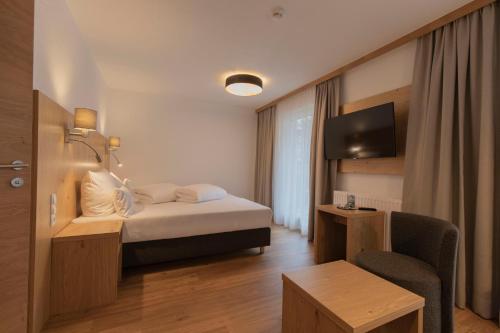 a hotel room with a bed and a chair at Berghotel Rasis in Galtür