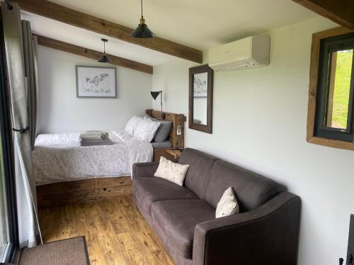 sala de estar con sofá y cama en Impeccable shepherds hut sleeping up to 4 guests, en Minehead