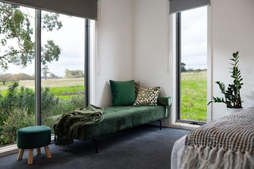 a bedroom with a green couch and large windows at Manna Gums- beautiful secluded setting in Daylesford