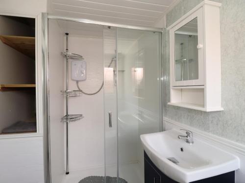 une salle de bain blanche avec une douche et un lavabo dans l'établissement Swiss Cottage, à Bridlington