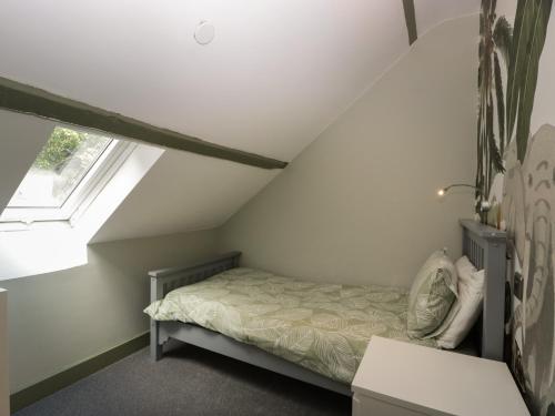 a small attic bedroom with a bed and a window at Pen-Croeslan Bach in Crickhowell