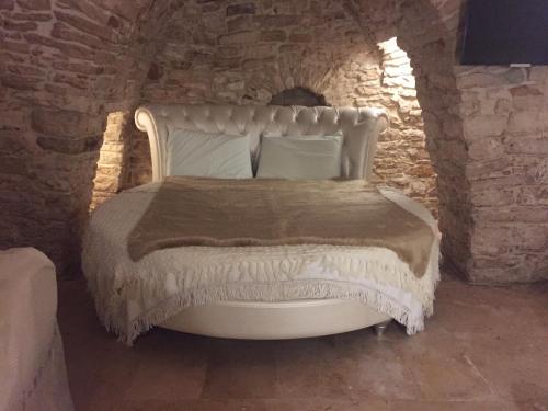 1 dormitorio con 1 cama blanca en una pared de piedra en Locus Amoenus Luxury rooms, en Terlizzi