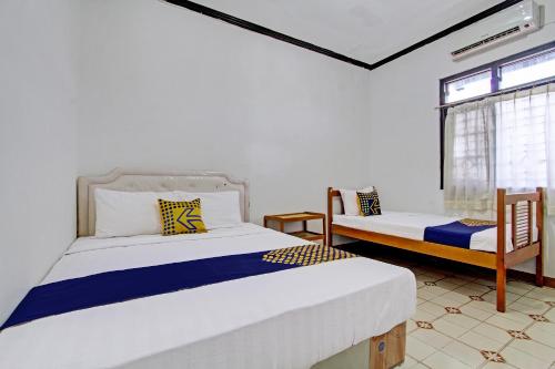 a bedroom with two beds and a window at SPOT ON 92623 Mw 46 Guesthouse in Yogyakarta