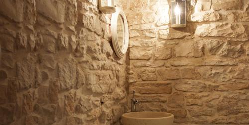 un bagno in pietra con lavandino e parete in pietra di Locus Amoenus Luxury rooms a Terlizzi