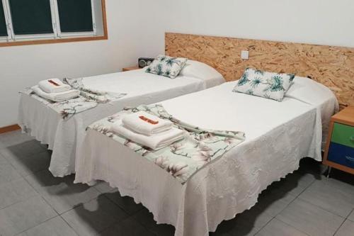 duas camas num quarto de hotel com toalhas em Cantinho do Cruzeiro Lajes em Lajes