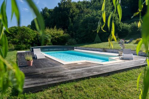 een zwembad met 2 stoelen en een houten terras bij L'Herbe Haute in Honfleur