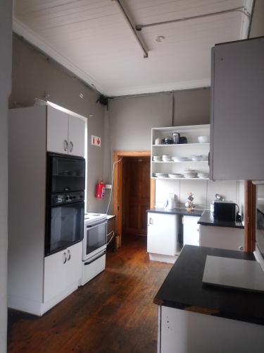 cocina con electrodomésticos blancos y suelo de madera en Hostel Villa Nova, en Mossel Bay