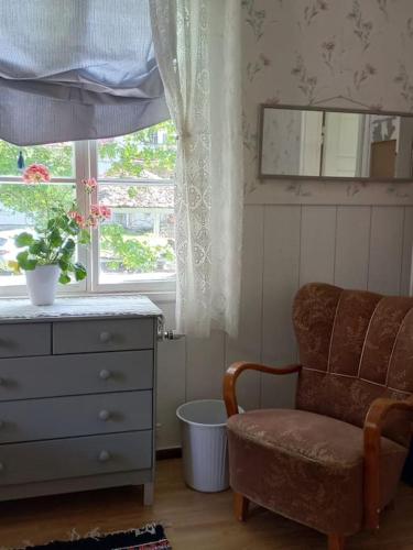 a bedroom with a dresser and a chair and a window at Bobackan pihatorppa Hauholla in Alvettula
