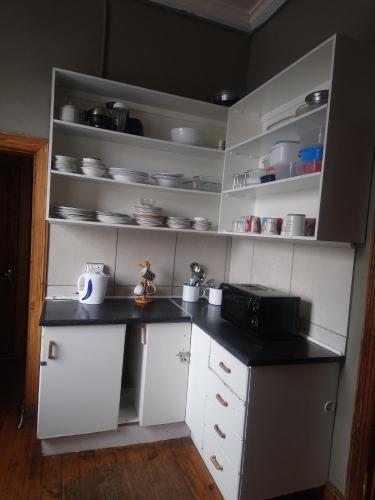 cocina con armarios blancos y encimera negra en Hostel Villa Nova, en Mossel Bay