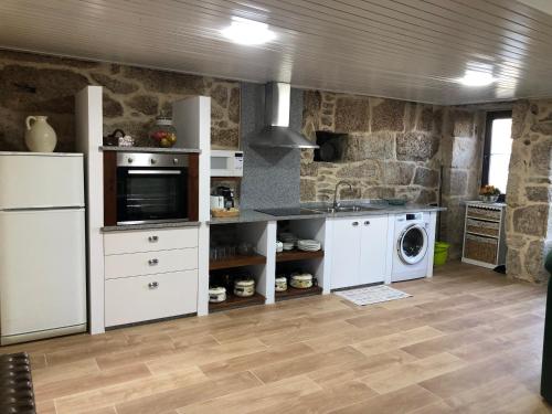kuchnia z białymi urządzeniami i kamienną ścianą w obiekcie Casa Lisboana w mieście Pontevedra