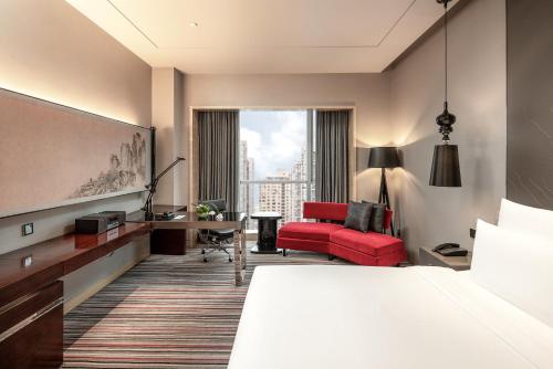 a hotel room with a bed and a red chair at Le Meridien Chongqing Nan'an in Chongqing