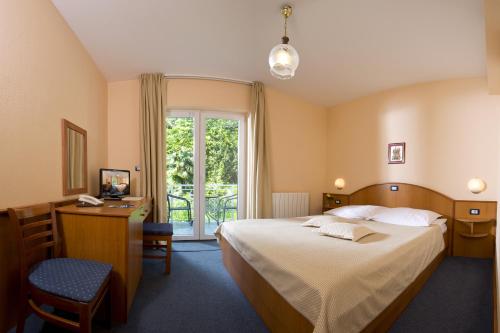 a hotel room with a bed and a desk and a window at Hotel Stanger in Lovran