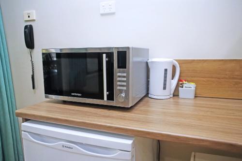 a microwave sitting on top of a counter with a coffee mug at Chambers Wildlife Rainforest Lodges in Lake Eacham