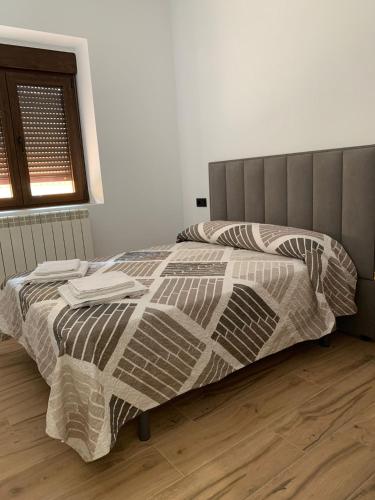 ein Schlafzimmer mit einem Bett mit einer Bettdecke und einem Fenster in der Unterkunft Apartamentos el Sabinar in Anchuela del Campo