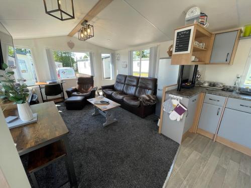 uma cozinha e uma sala de estar com um sofá e uma mesa em 6 Rannoch, lovely holiday static caravan for dogs & their owners. em Forfar