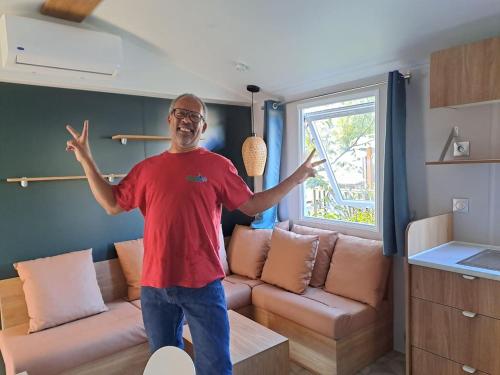a man standing in a living room with his hands in the air at Mobile-home dans camping 4 étoiles in Condrieu