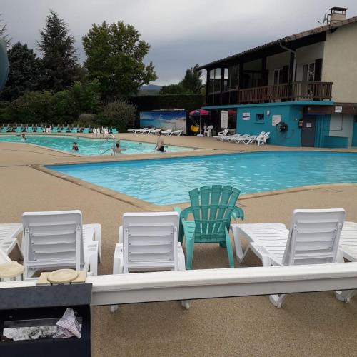 a swimming pool with chairs and people in the water at Mobile-home dans camping 4 étoiles in Condrieu