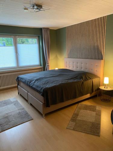 una camera con un grande letto in una stanza con due finestre di Eifelhaus LandLuft mit Infrarotkabine a Berlingen