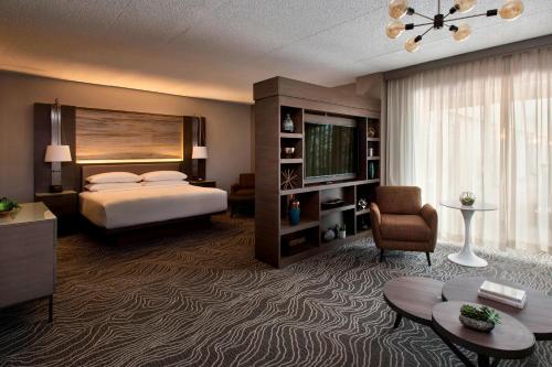 a hotel room with a bed and a living room at Marriott Melville Long Island in Melville