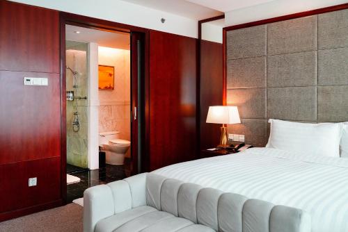 a bedroom with a large bed and a bathroom at Pullman Shanghai Skyway in Shanghai