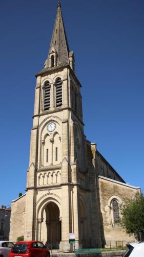 a church with a tower with a clock on it at 18 on the Rue in Eymet