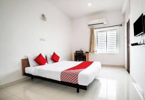 a bedroom with a bed with red pillows and a window at Flagship 82361 Black Pearl Residency in Pīlamedu