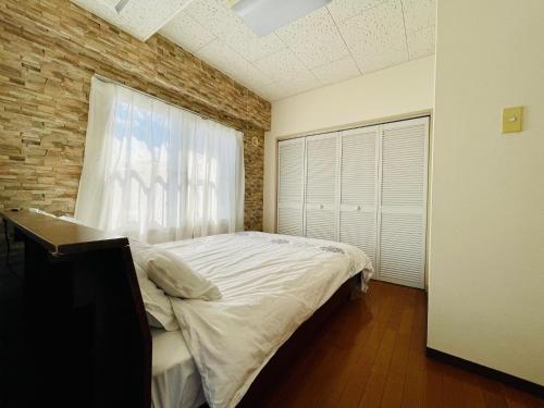 um quarto com uma cama branca e uma janela em 中島9-1　NEW OPEN　景観最良の1LDK50㎡の室内空間　地下鉄駅徒歩5分以内 em Toyohira