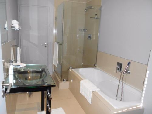 a bathroom with a tub and a sink and a shower at 101Infinity in Bloubergstrand