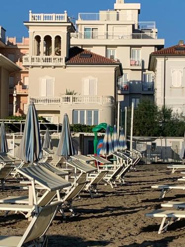 a row of lounge chairs and umbrellas on a beach at Villa La Torretta Luxury B&B - Adults Only - in Rimini