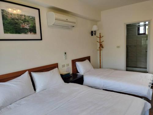 two beds in a hotel room with white sheets at Happy Inn in Juguang