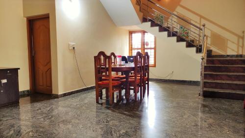 uma sala de jantar com mesa, cadeiras e escadas em Kurumbalakotta Village Homestay em Padinjarathara