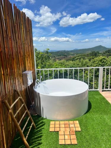 a bath tub sitting on the grass on a balcony at บ้านภูไผ่ ไร่ภูไผ่เบิกตะวัน in Ban Nam Phang