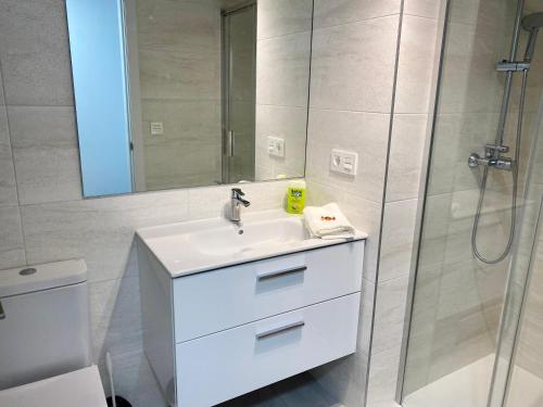 La salle de bains est pourvue d'un lavabo blanc et d'une douche. dans l'établissement VoraMar 3 Playa Puerto de Sagunto, à Sagonte