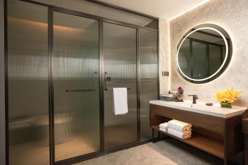 a bathroom with a shower and a sink and a mirror at UrCove By Hyatt ShenZhen Bay in Shenzhen