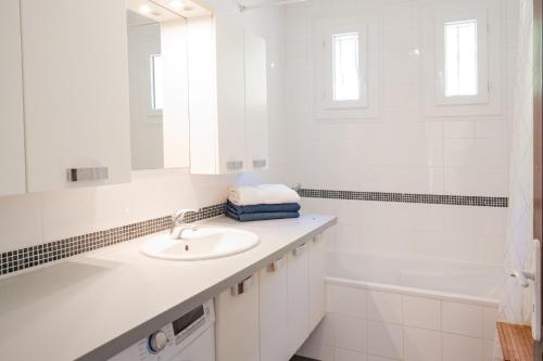 a white bathroom with a sink and a bath tub at Villa Colombes in Draguignan