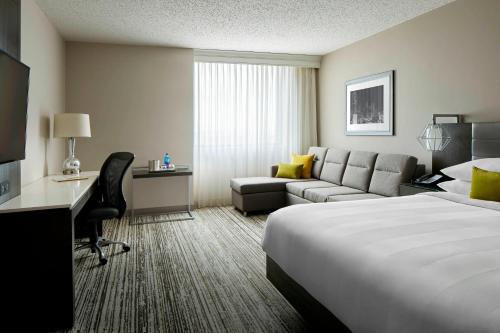 Cette chambre comprend un lit, un bureau et un canapé. dans l'établissement Marriott DFW Airport South, à Fort Worth