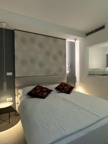 a bedroom with a white bed with two pillows on it at VENEZIANA Boutique Hotel Superior in Koper