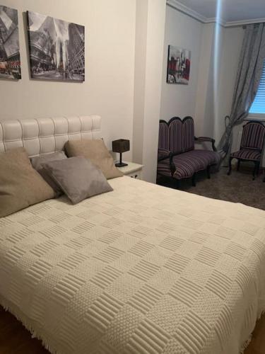1 dormitorio con 1 cama blanca grande y 2 sillas en Alba de Tormes Salamanca Piso de 2 habitaciones 3 camas, en Alba de Tormes