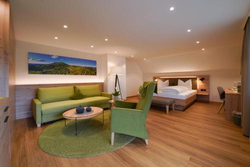 a hotel room with a green couch and a bed at Berggasthaus Braunbergstüble in Oppenau