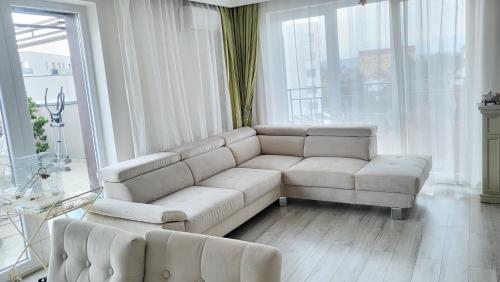 een woonkamer met een witte bank en een groot raam bij SIBIU Bach Penthouse in Sibiu