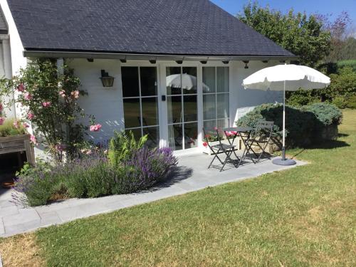 a patio with an umbrella and a table and chairs at Clair Matin in Malmedy