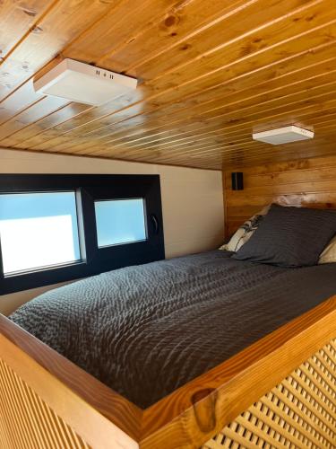 - un lit dans une petite maison avec 2 fenêtres dans l'établissement Tiny House Piscine et Spa, à Gaillac