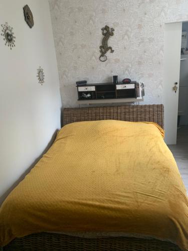 une chambre avec un lit avec une couverture jaune dans l'établissement JOUANNEAU, au Mans